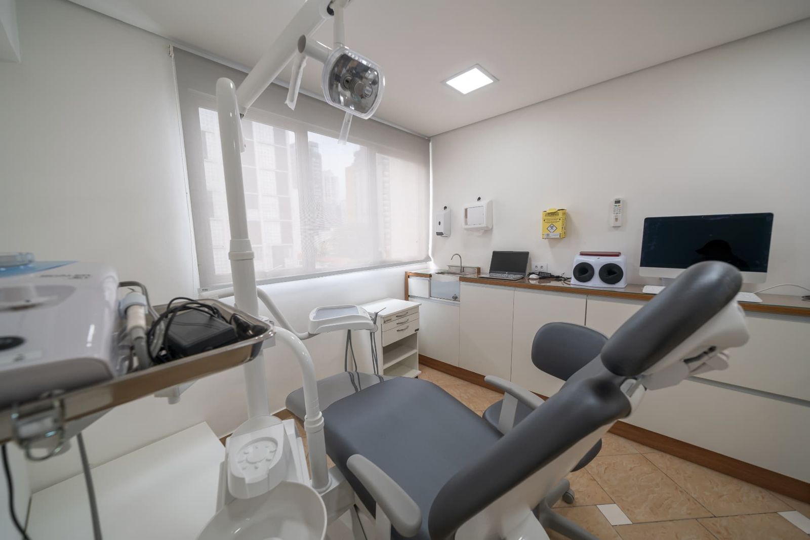 Sala odontológica iluminada com bancada, computador e janela