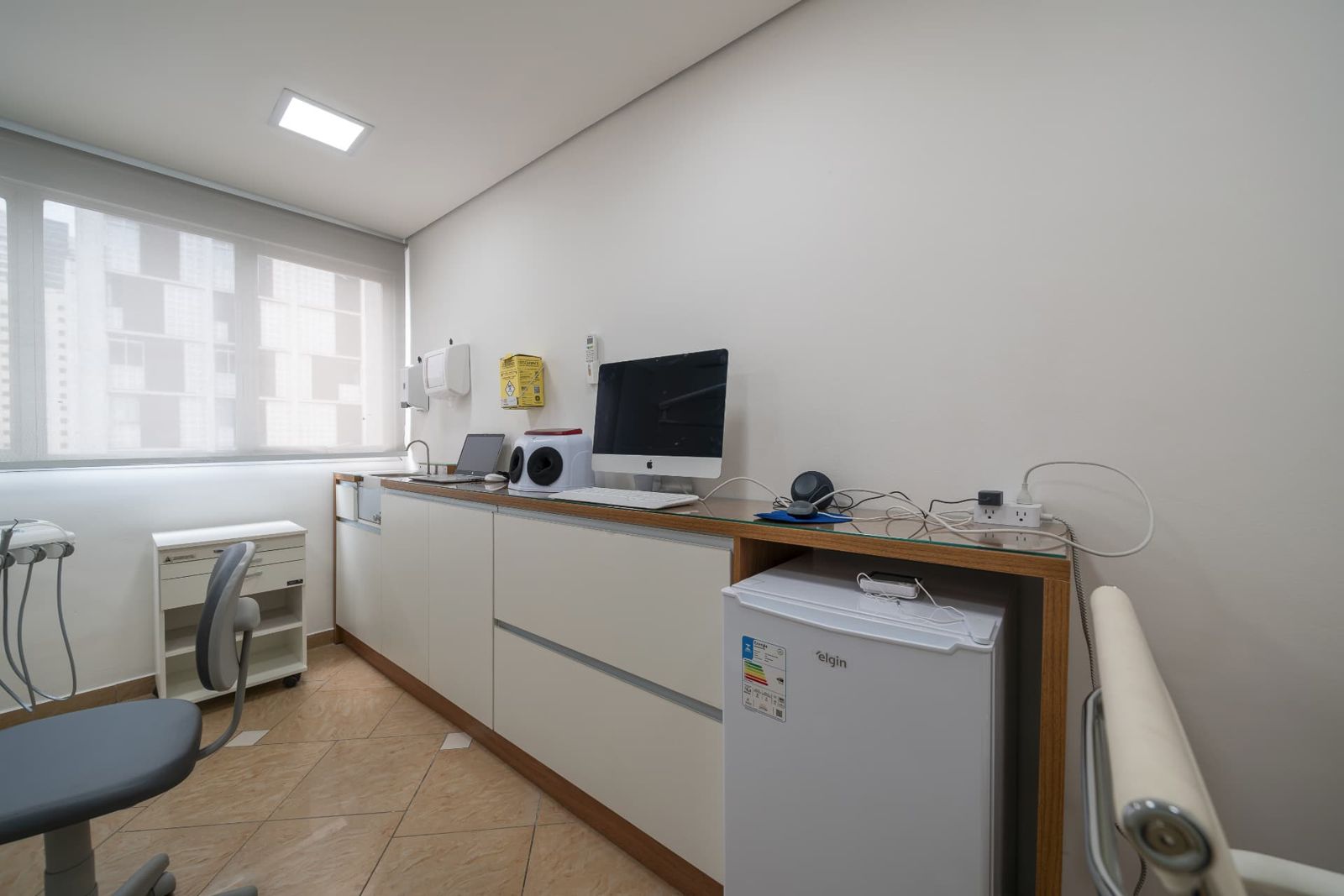 Sala odontológica ampla com cadeira, equipamentos e vista da cidade