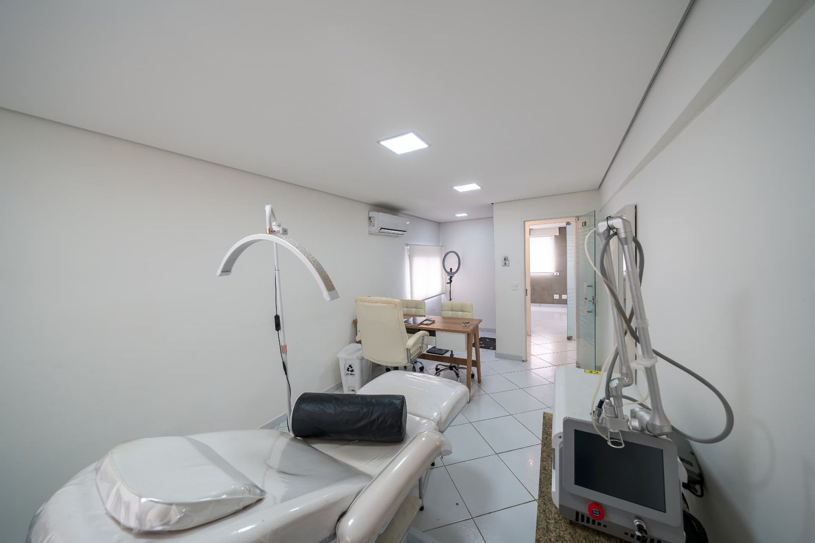 Sala de estética com maca reclinável, foco de luz e aparelho a laser