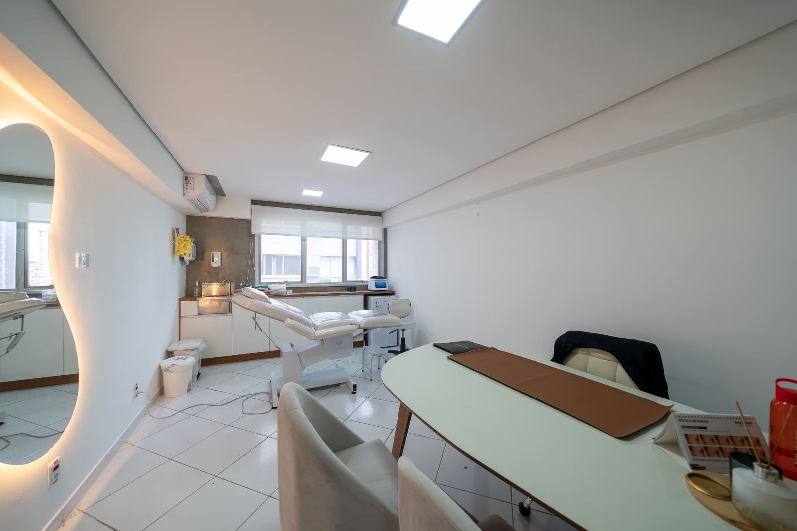Sala de procedimentos ampla com maca e espelho iluminado