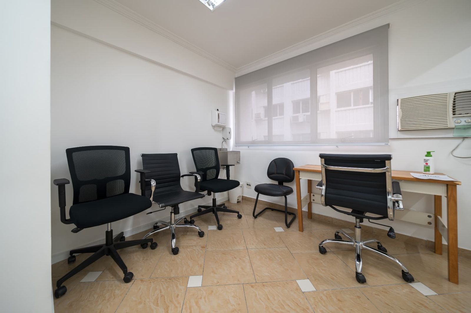 Consultório clínico com mesa, cadeiras e pia