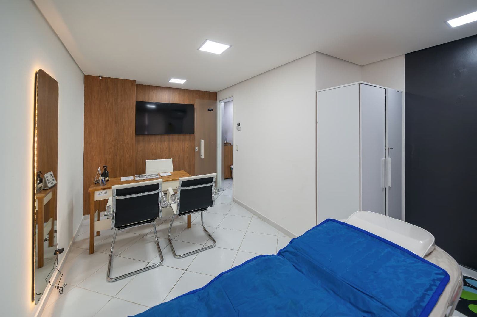 Consultório com mesa, TV e armário para materiais