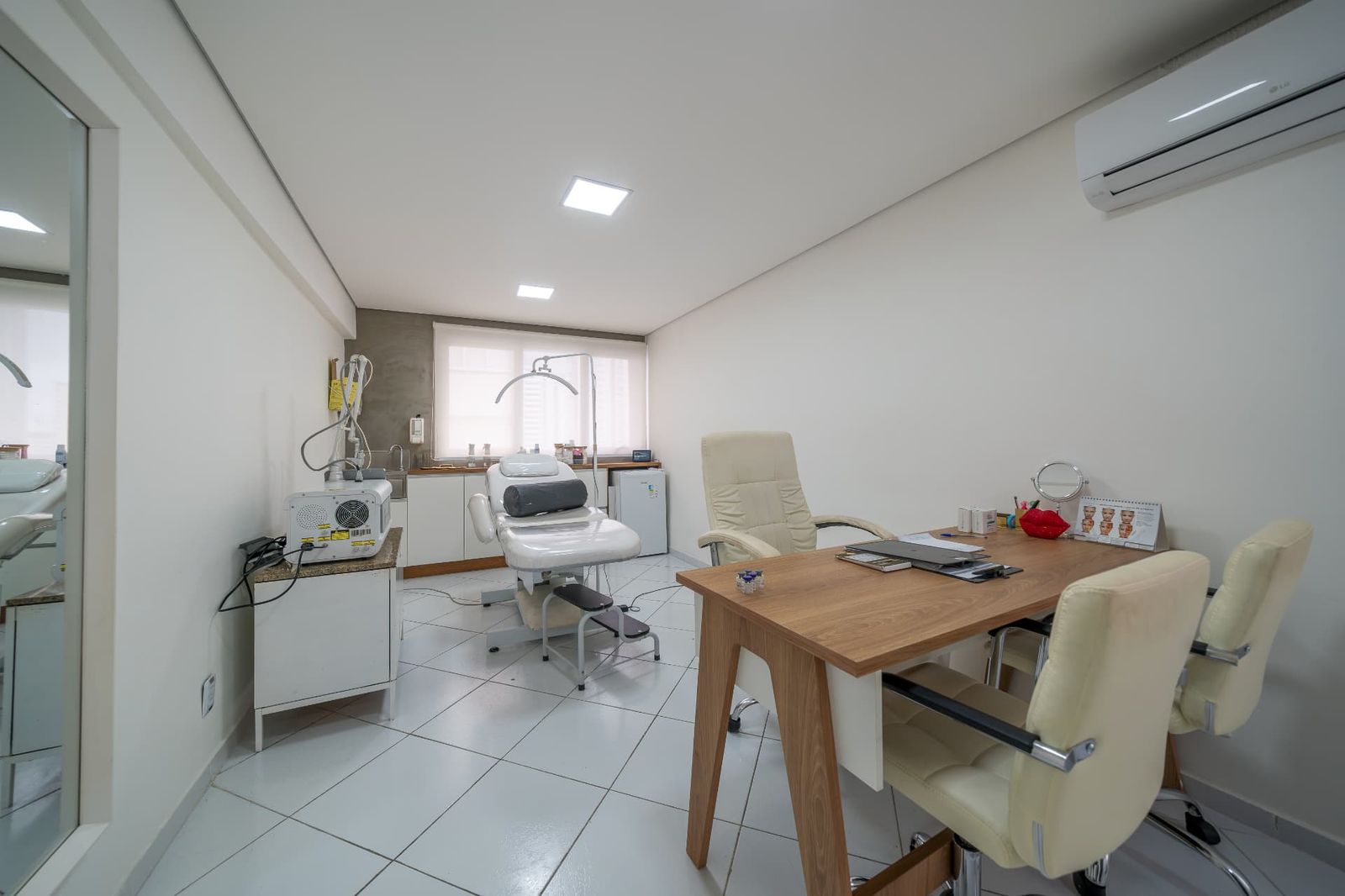 Sala com maca, aparelhos de estética e mesa de trabalho