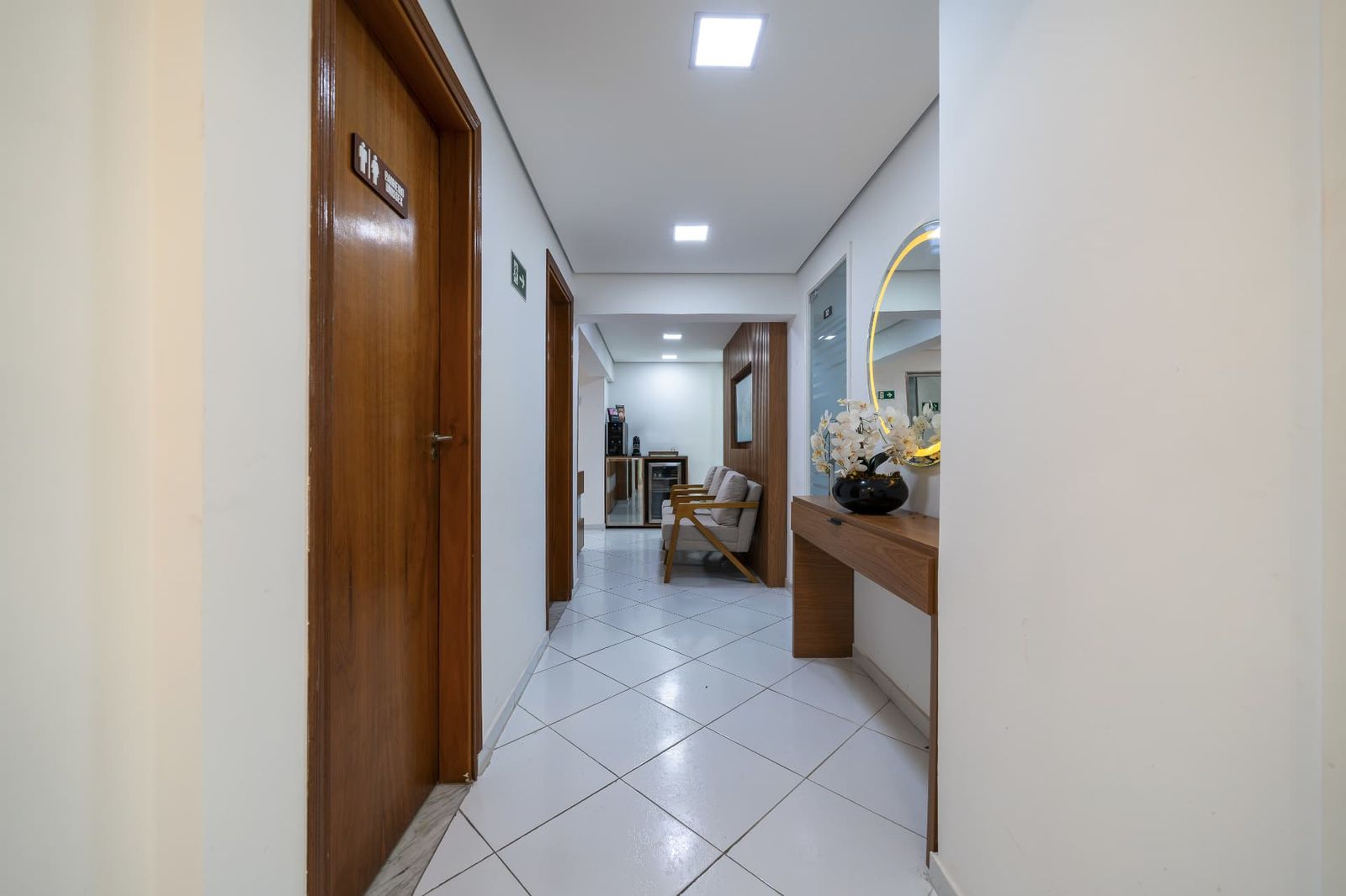 Corredor da clínica com espelho e sala de espera ao fundo