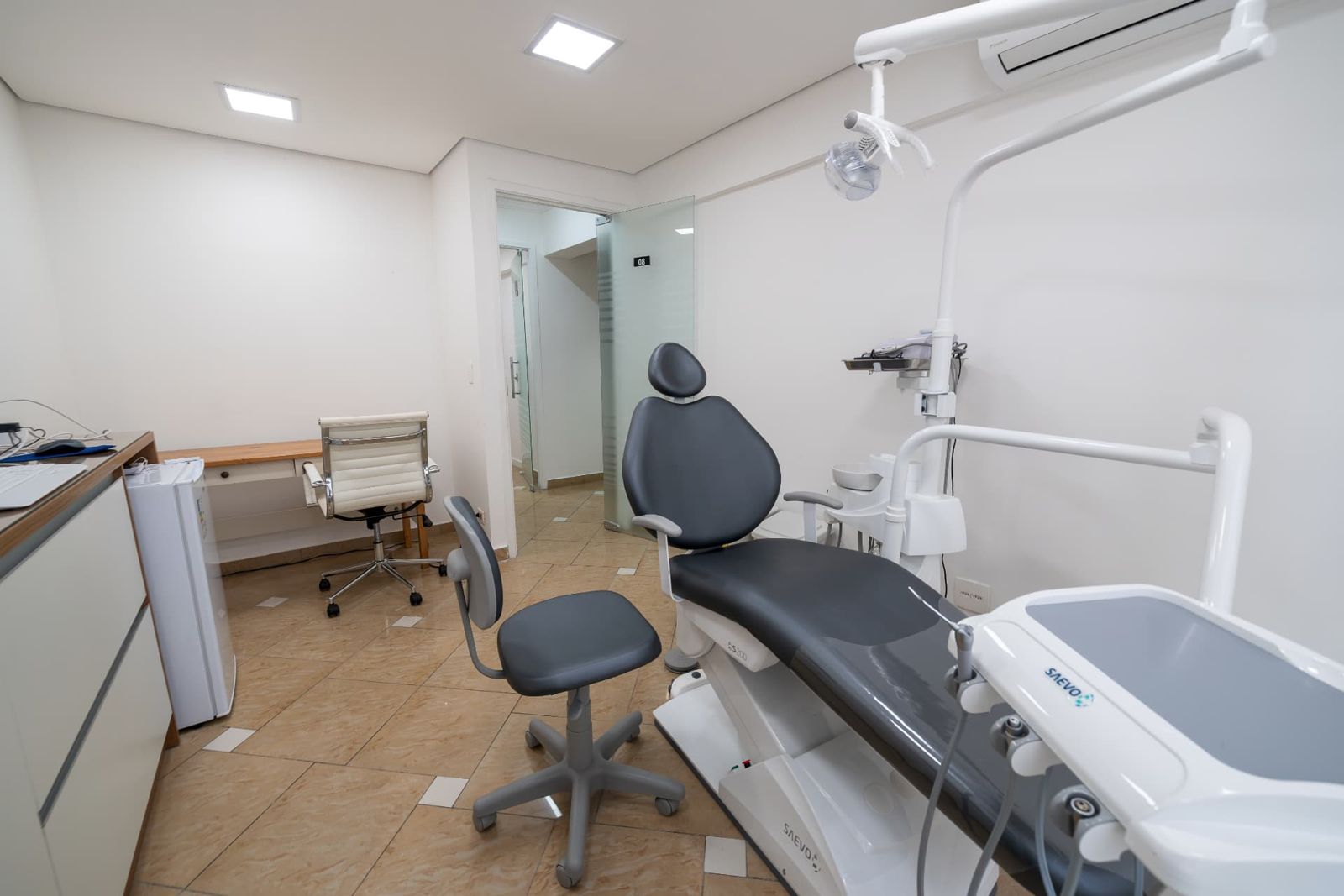 Consultório odontológico com cadeira, mesa de apoio e mocho